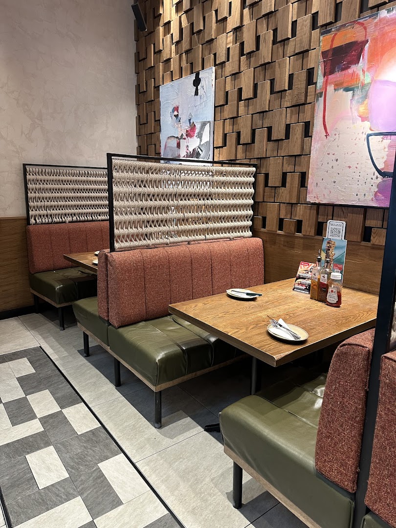 Interior shot of Nandos restaurant with booth seating, tables, and modern decor.