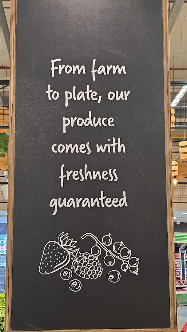 A chalkboard sign with white text and illustrations of berries, promoting fresh produce.