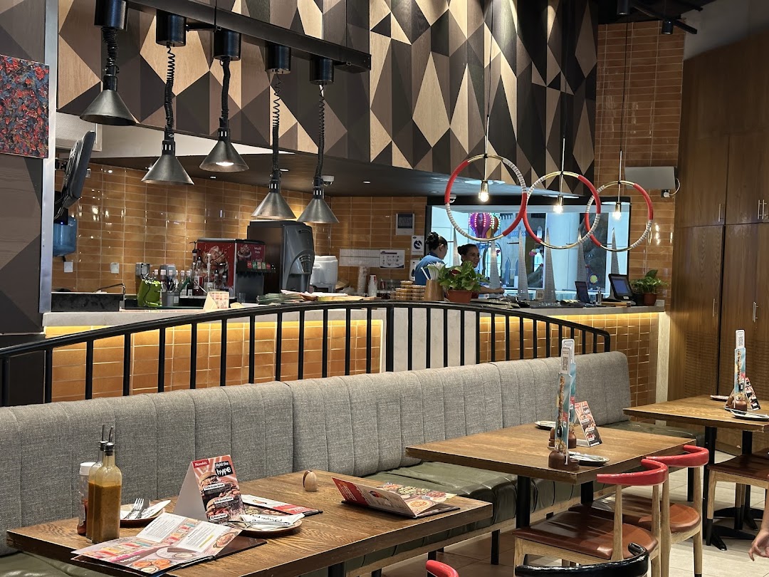 Interior view of a Nandos restaurant with tables, seating, and a counter area.