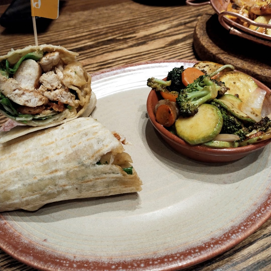 A delicious chicken wrap served with a side of roasted vegetables on a plate.