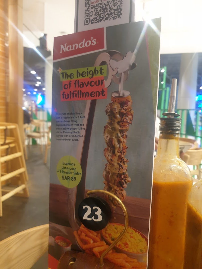 A Nando's menu board displays a PERI-PERI chicken espetada with sides.