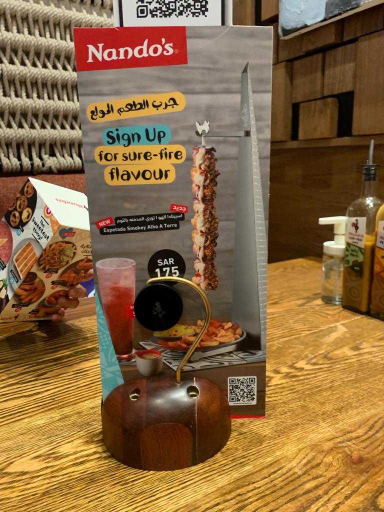 A Nando's promotional stand featuring a new Espetada Smokey Alho A Torre dish.