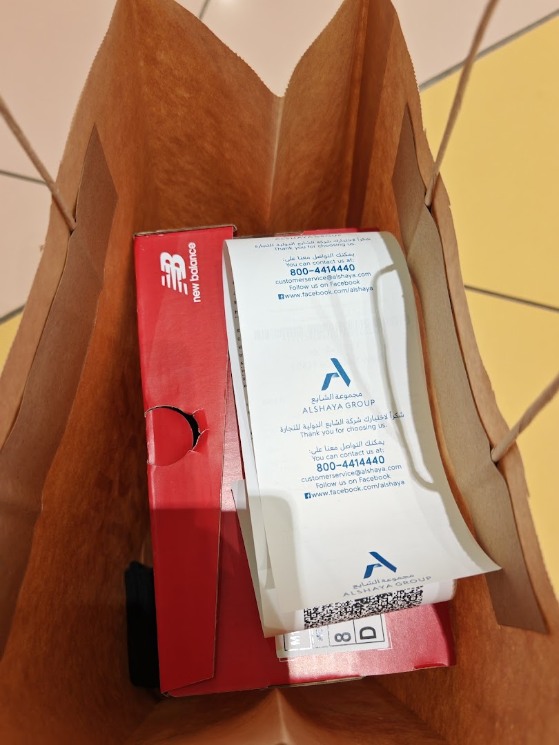 A New Balance shopping bag containing a red shoebox and a receipt.