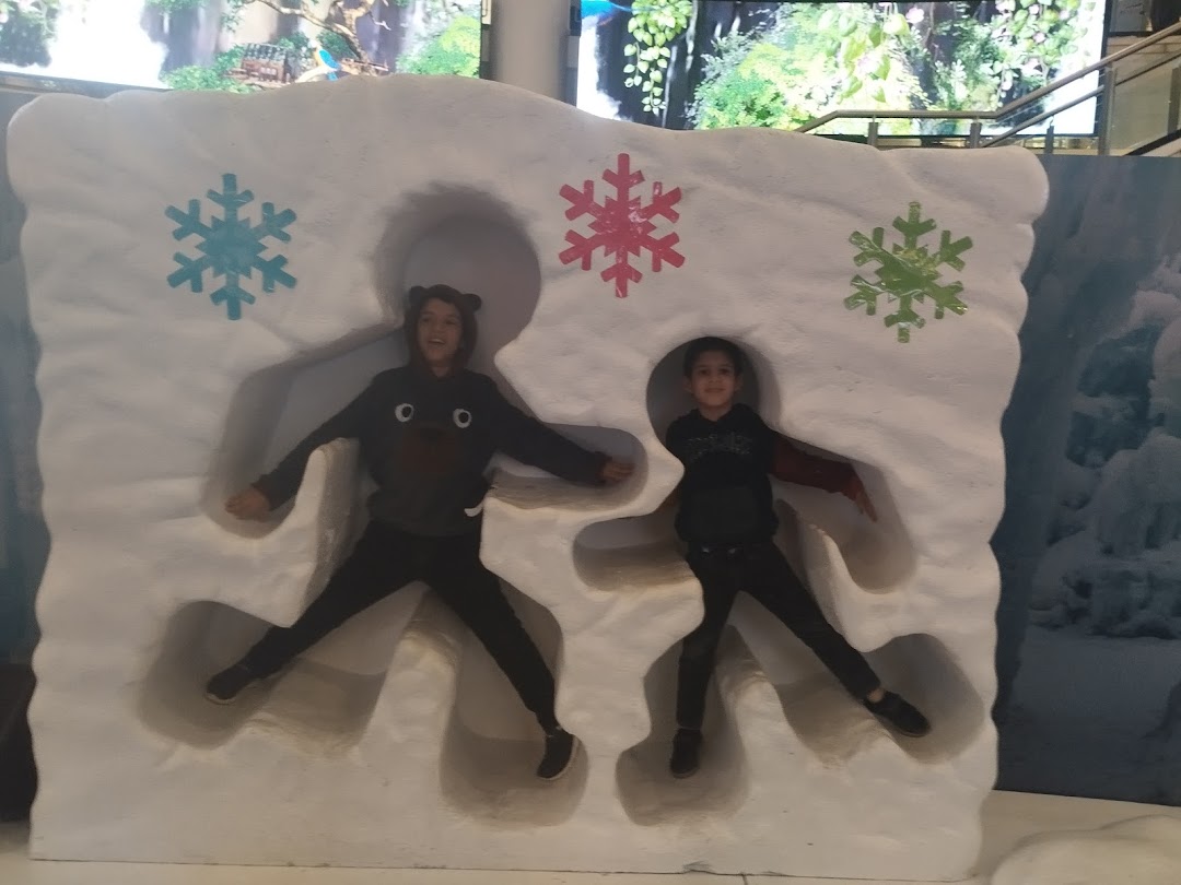 Two children posing in a snow-themed cutout with snowflakes.
