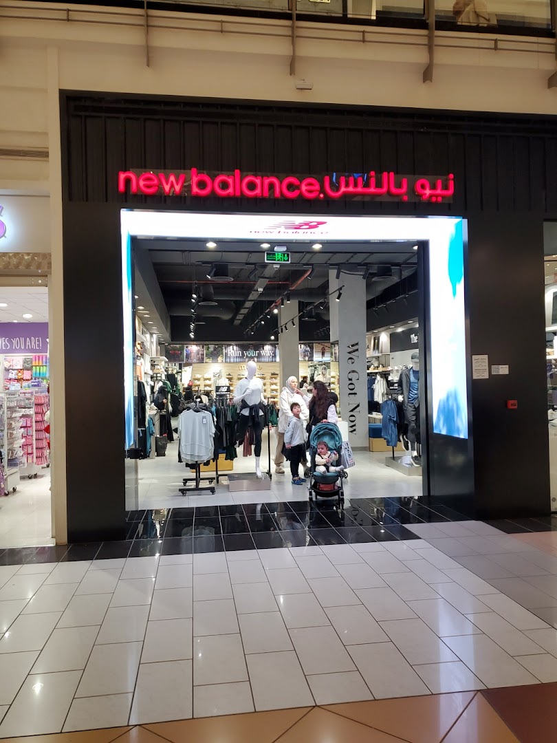The entrance to a New Balance store with clothing displays and mannequins visible inside.