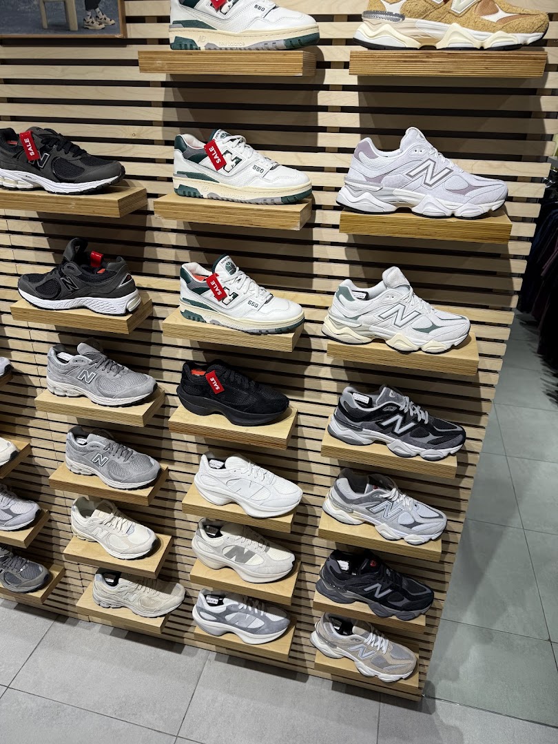 A wall display showcasing a variety of New Balance sneakers on wooden shelves.