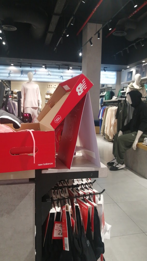 New Balance store interior with clothing displays and mannequins.