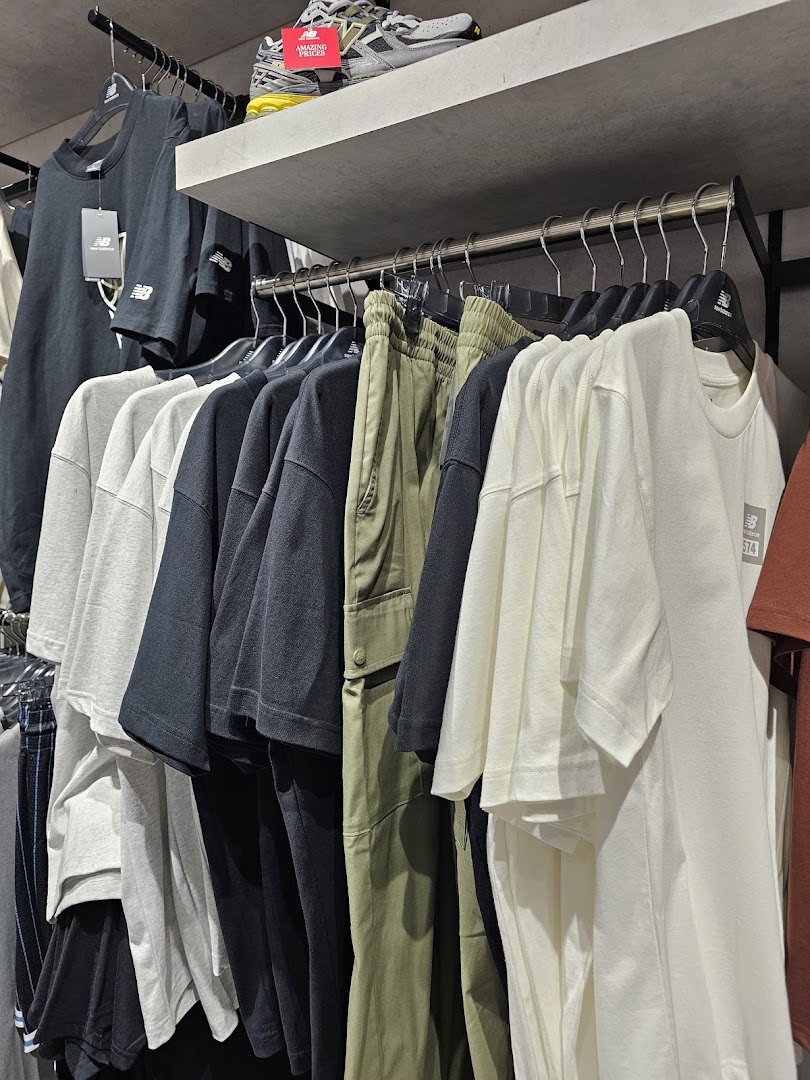 New Balance store interior showcasing a variety of apparel including t-shirts and pants on display.