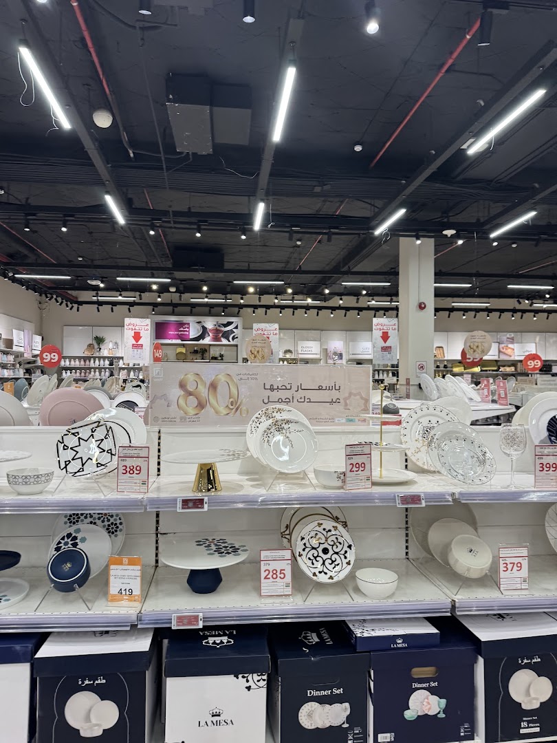 A display of dinnerware and tableware sets with prices in a retail store.