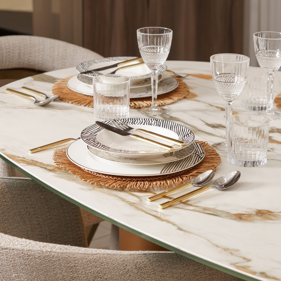 A beautifully set dining table with elegant plates, cutlery, glassware, and placemats.