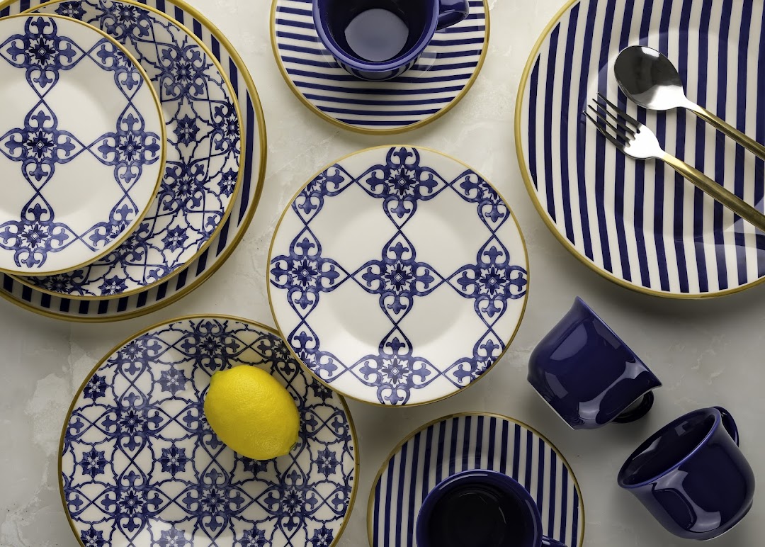 A collection of blue and white patterned plates, cups, and cutlery with gold trim.