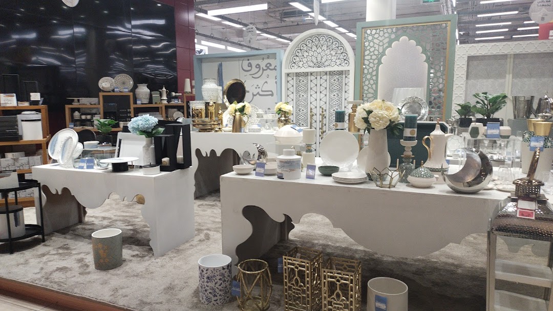 A display of decorative home goods, including vases, plates, and lanterns, arranged on white tables.