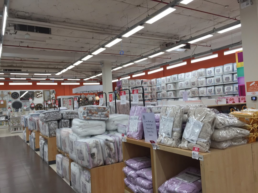 A wide aisle in a store displaying packaged bedding and home goods on shelves and displays.
