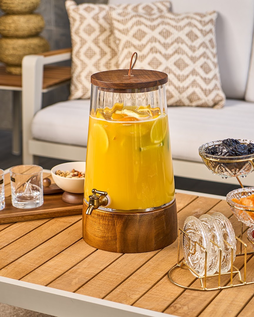 A refreshing beverage dispenser filled with citrus-infused juice on a wooden table.