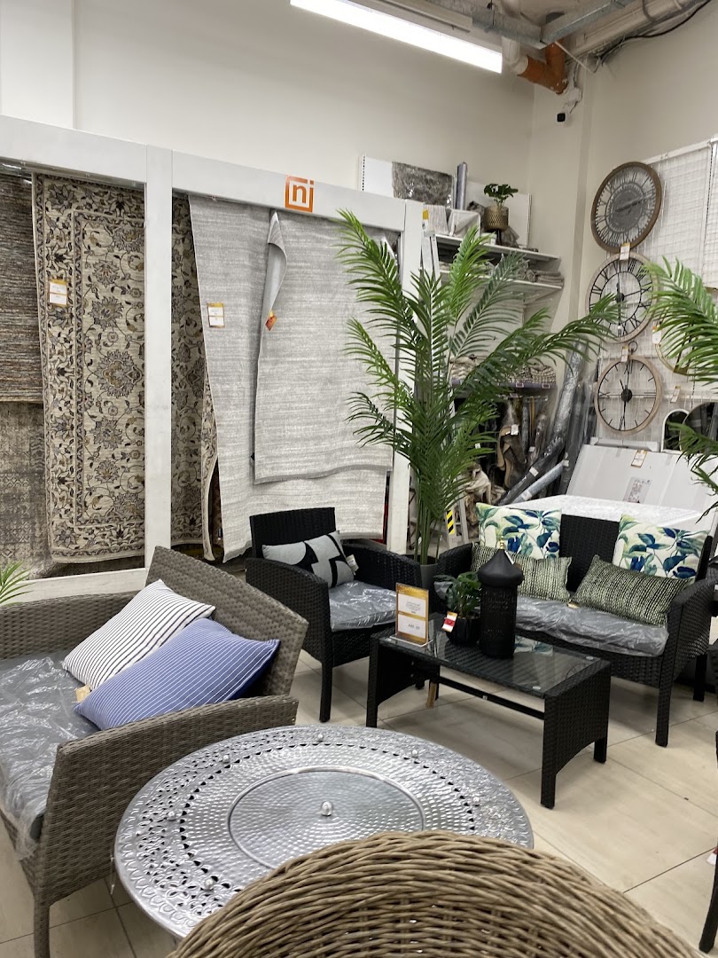 Interior view of a store displaying outdoor furniture and rugs.