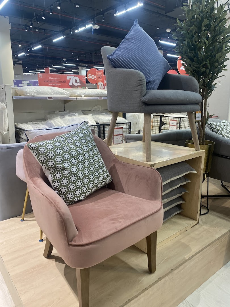 Two stylish chairs with decorative pillows are displayed in a retail store.