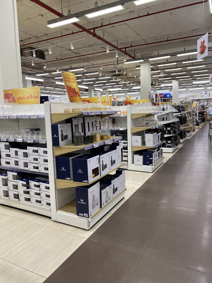 A wide aisle in a store, showcasing shelves stocked with glassware and boxed kitchenware.