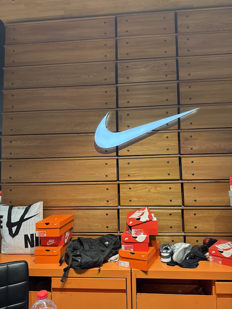 Nike store interior with shoe boxes, a tote bag, and a duffel bag on display.