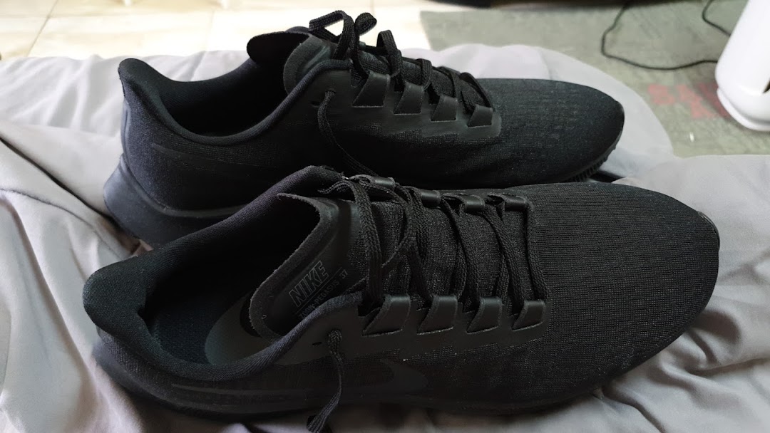 A pair of black Nike Zoom Pegasus running shoes are displayed on a soft surface.