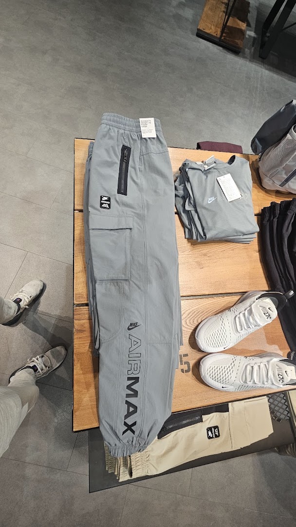 Nike Air Max pants and sneakers displayed on a wooden table in a store.