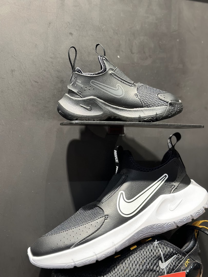 Close-up view of black Nike slip-on sneakers displayed on shelves.