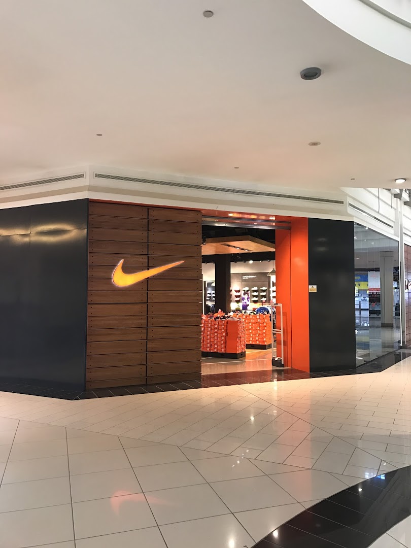 The entrance of a Nike store with its iconic logo and displays of merchandise.