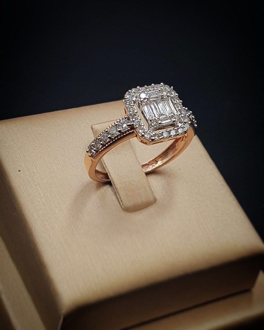 A stunning rose gold ring with a central emerald-cut diamond surrounded by smaller diamonds.