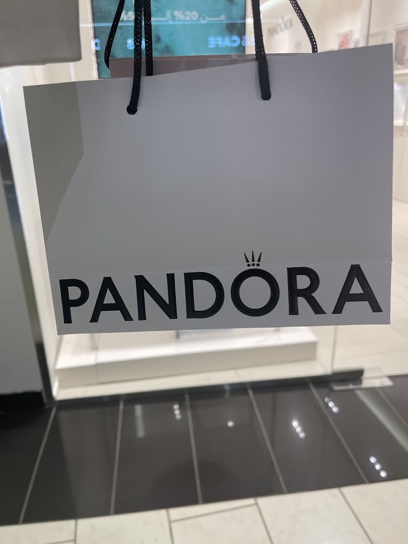 A white Pandora shopping bag with the brand's logo is displayed in front of a store.