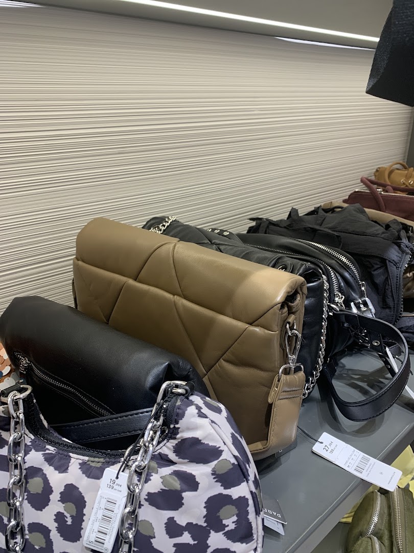 A display of various stylish handbags, including leopard print, black, and quilted designs.