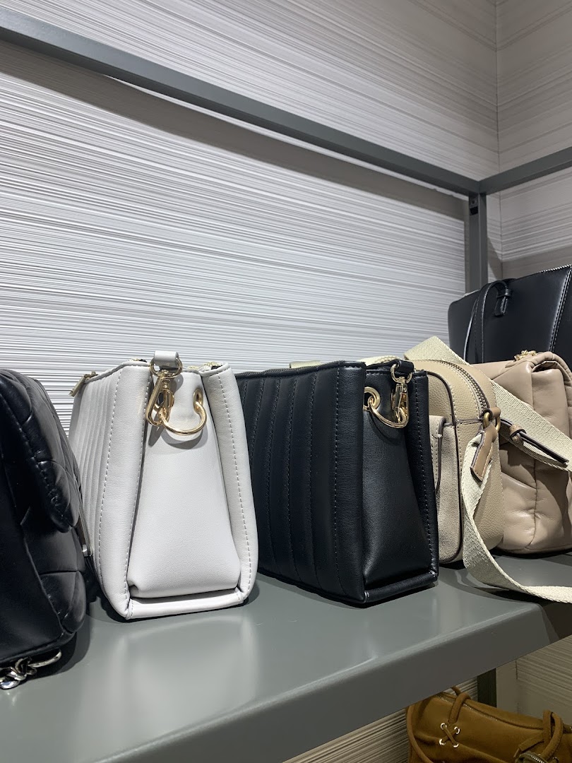 A selection of stylish handbags in various colors displayed on a shelf.