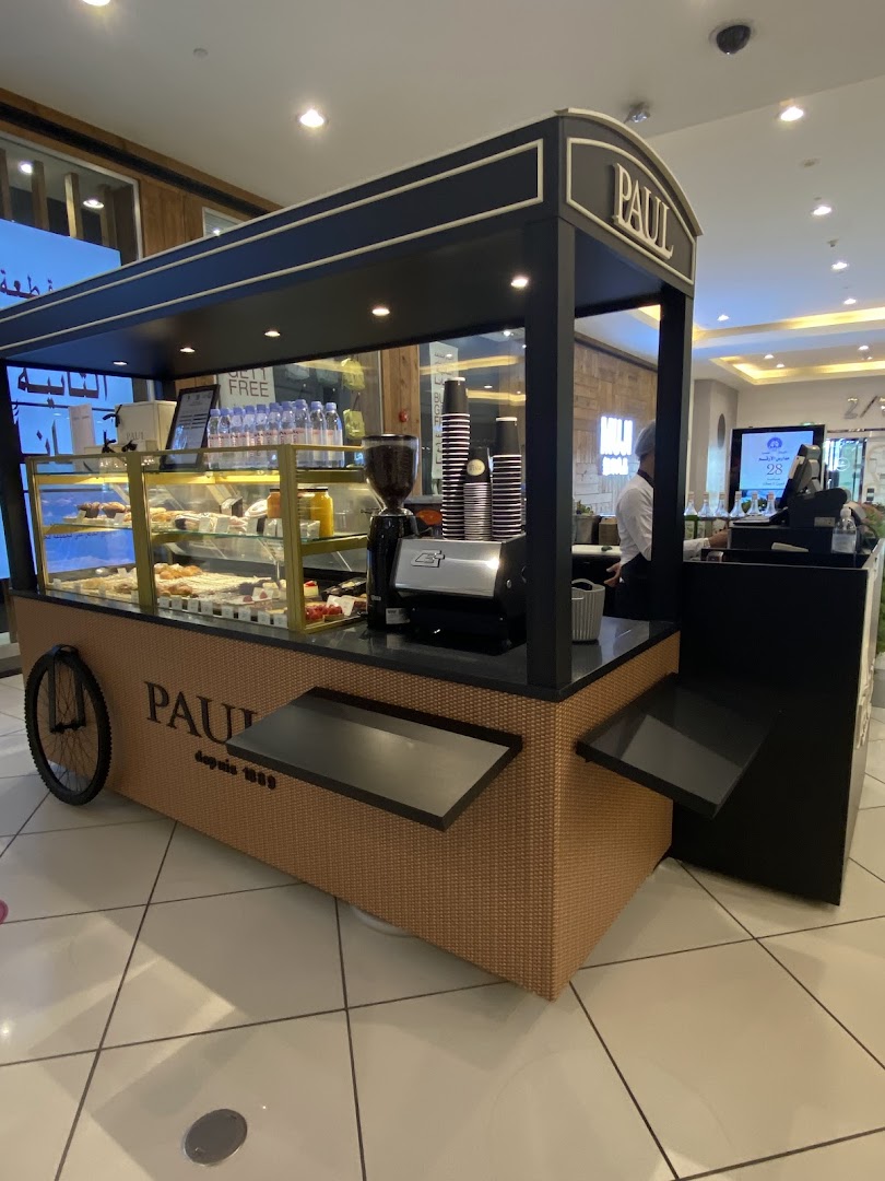 A Paul cafe kiosk with pastries and coffee equipment inside a shopping mall.