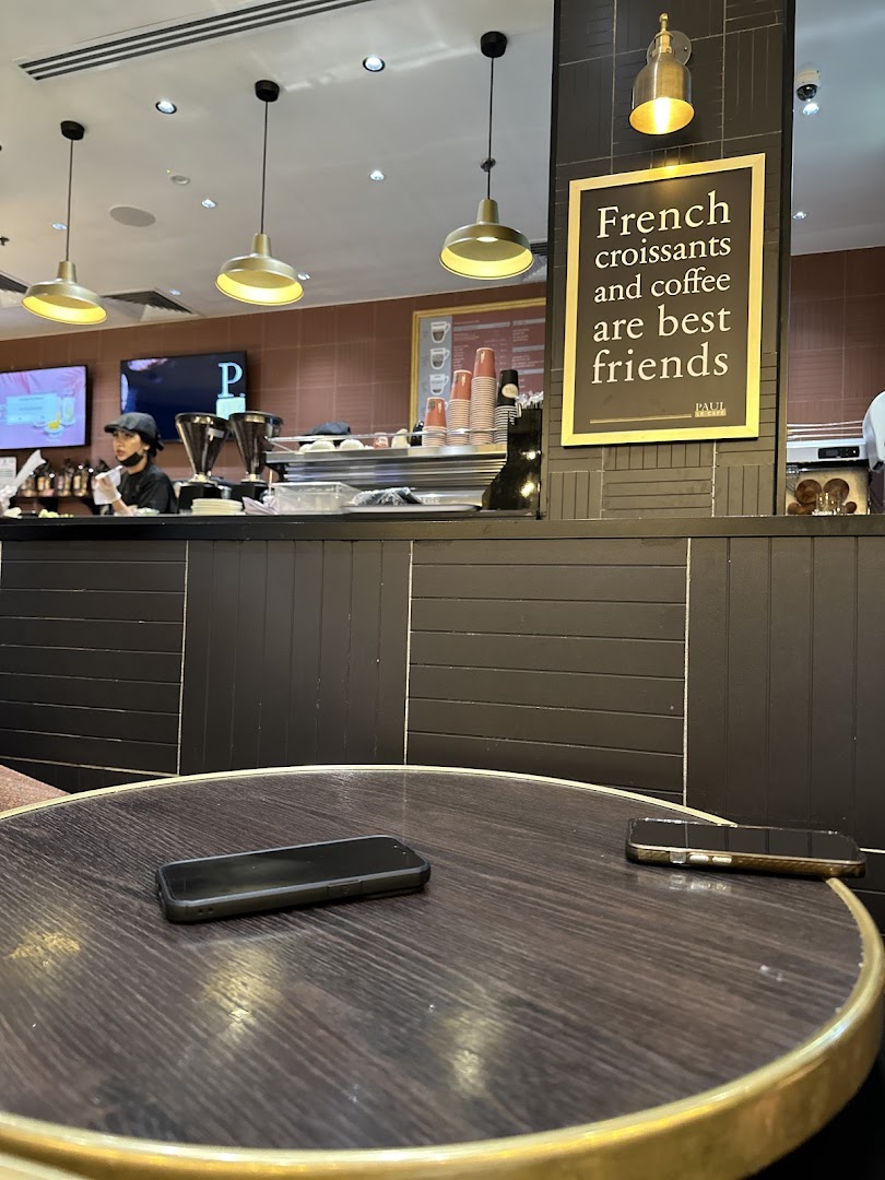 A cafe interior with a counter, barista, and a table with phones.