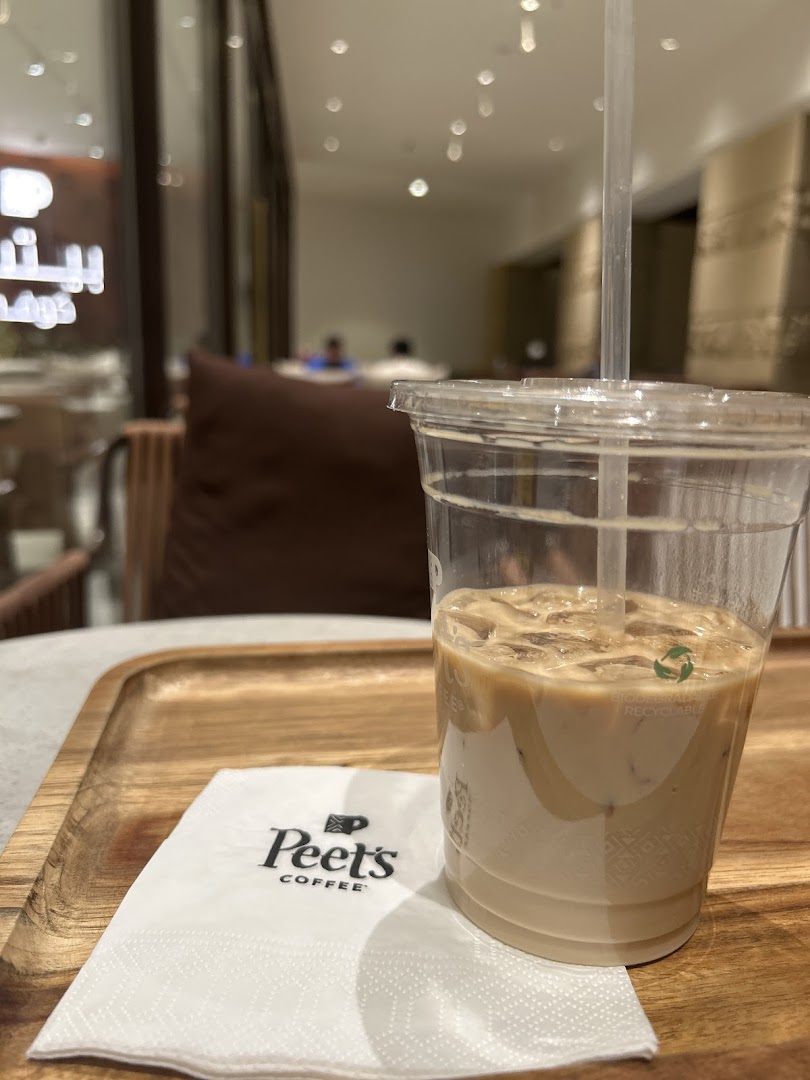 A refreshing iced coffee from Peet's Coffee served on a wooden tray with a branded napkin.