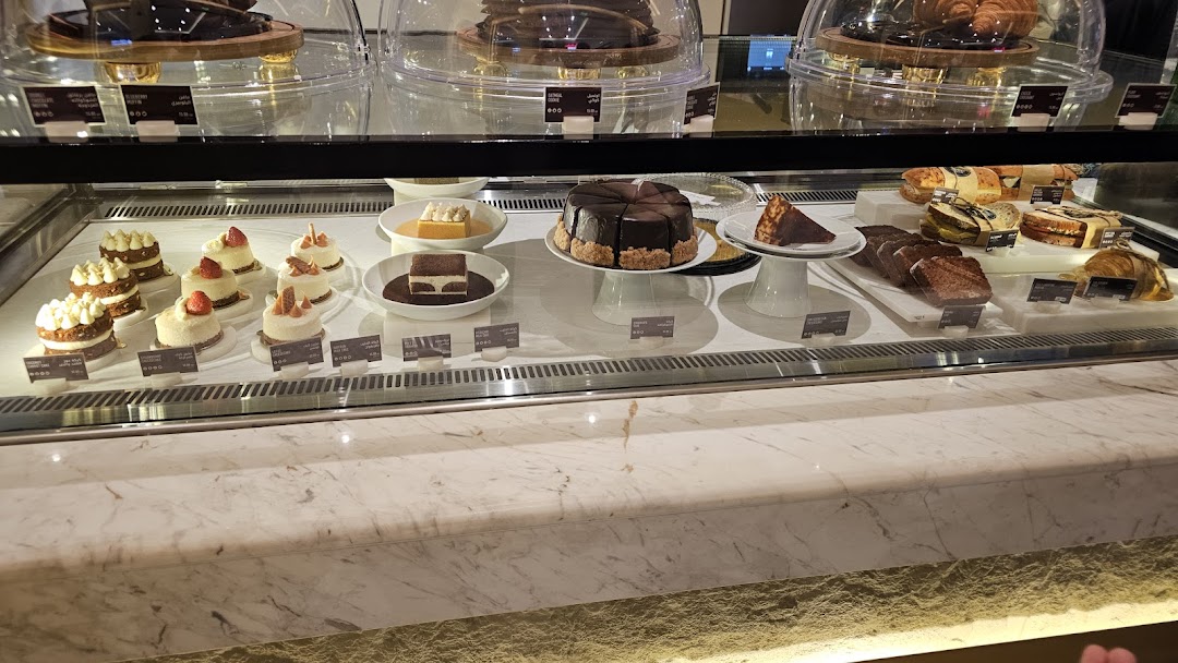 A display case filled with various pastries, cakes, and sandwiches.