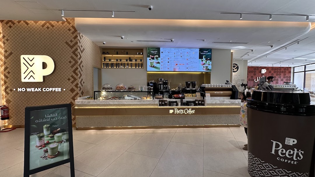 The interior of a modern Peet's Coffee shop with a prominent counter and digital menu.