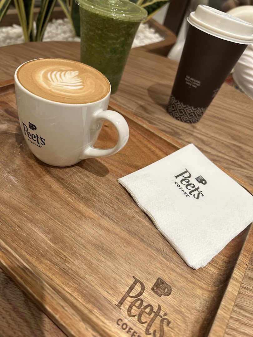 A close-up of a latte with latte art and a green smoothie on a wooden tray.