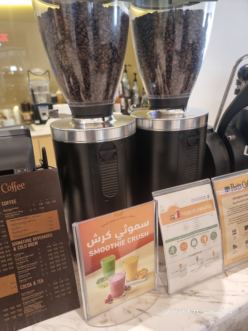 A close-up of coffee grinders and a menu board at Peet's Coffee.