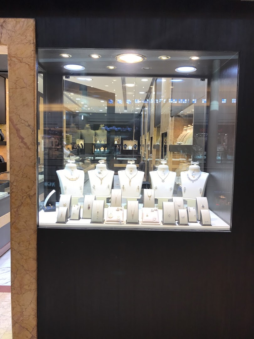 A well-lit jewelry display case showcasing necklaces, earrings, and rings on white stands.