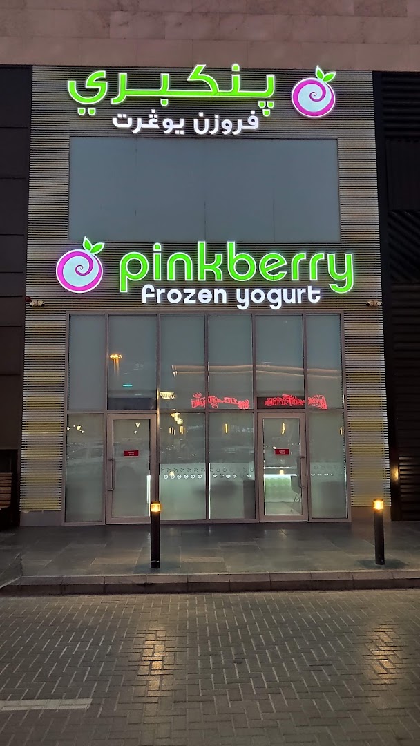 The exterior of a Pinkberry frozen yogurt shop with illuminated signage.