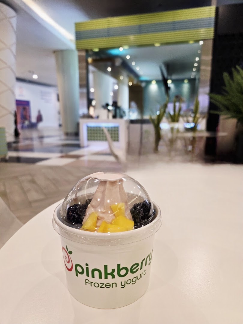 A cup of Pinkberry frozen yogurt with blackberries and mango toppings.