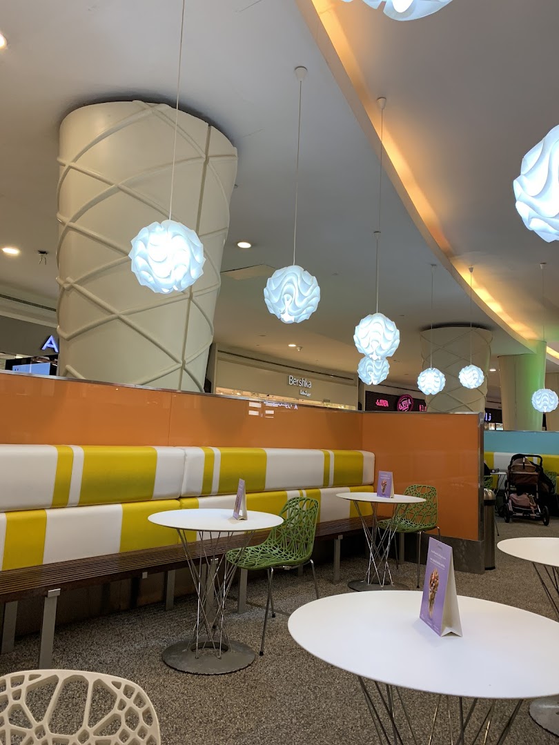 Interior of a Pinkberry shop with colorful seating, modern tables, and decorative lighting.