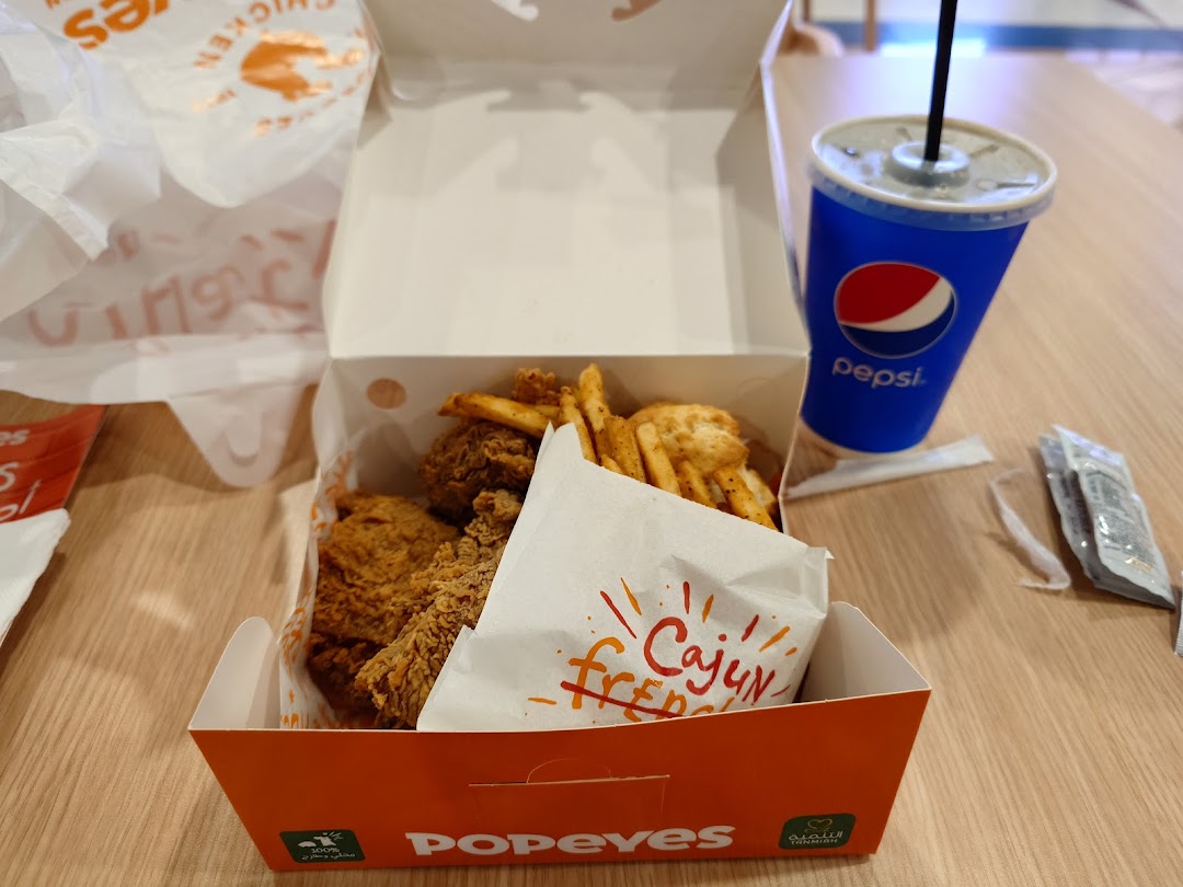 A box of Popeyes fried chicken and fries with a Pepsi drink.