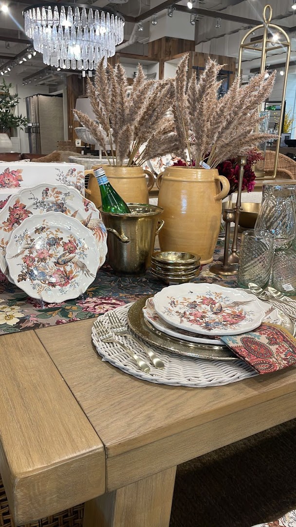 A beautifully set dining table with floral plates, champagne bucket, and decorative vases.