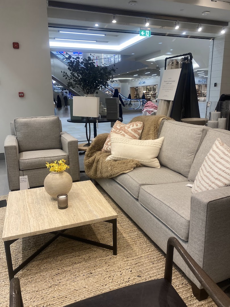 A Pottery Barn living room display featuring a grey sofa, armchair, coffee table, and decor.