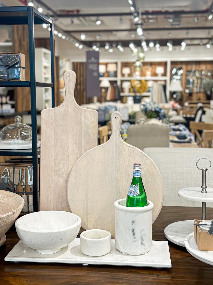 A display of wooden cutting boards, marble bowls, and a bottle of San Pellegrino water.