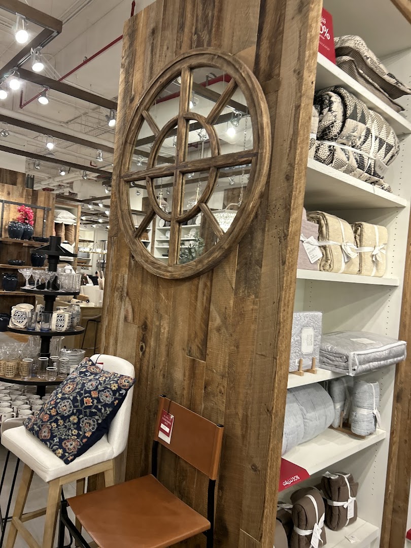 Interior shot of Pottery Barn showcasing home decor items like pillows, chairs, mirrors, and bedding.