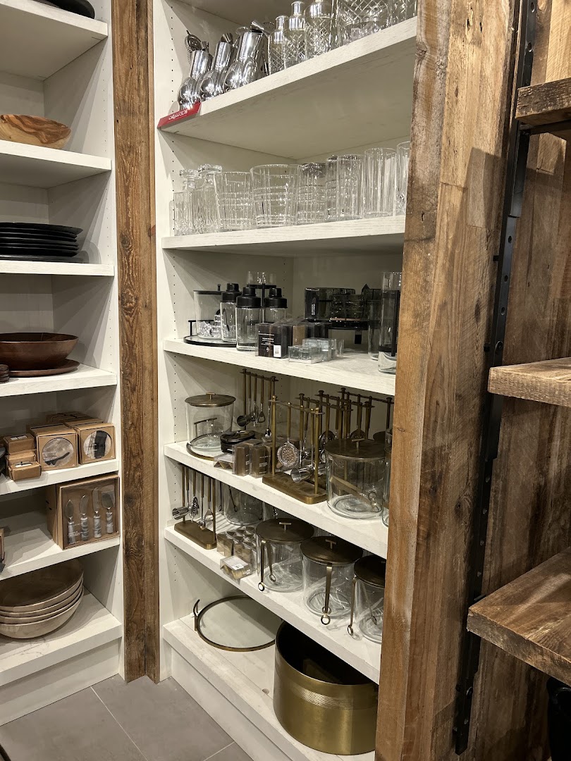 Shelves stocked with glassware, barware, and kitchen accessories in a retail store.