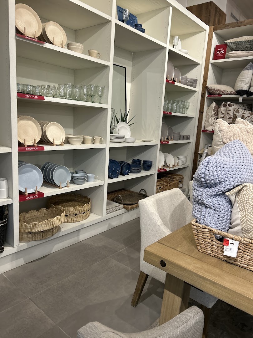 Shelves filled with dinnerware, glassware, blankets, and decorative baskets in a home goods store.