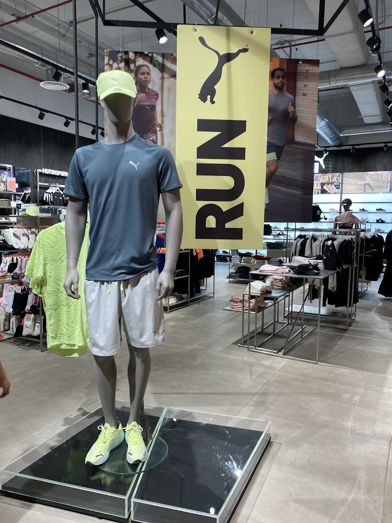 Mannequin dressed in PUMA running gear inside a brightly lit store.