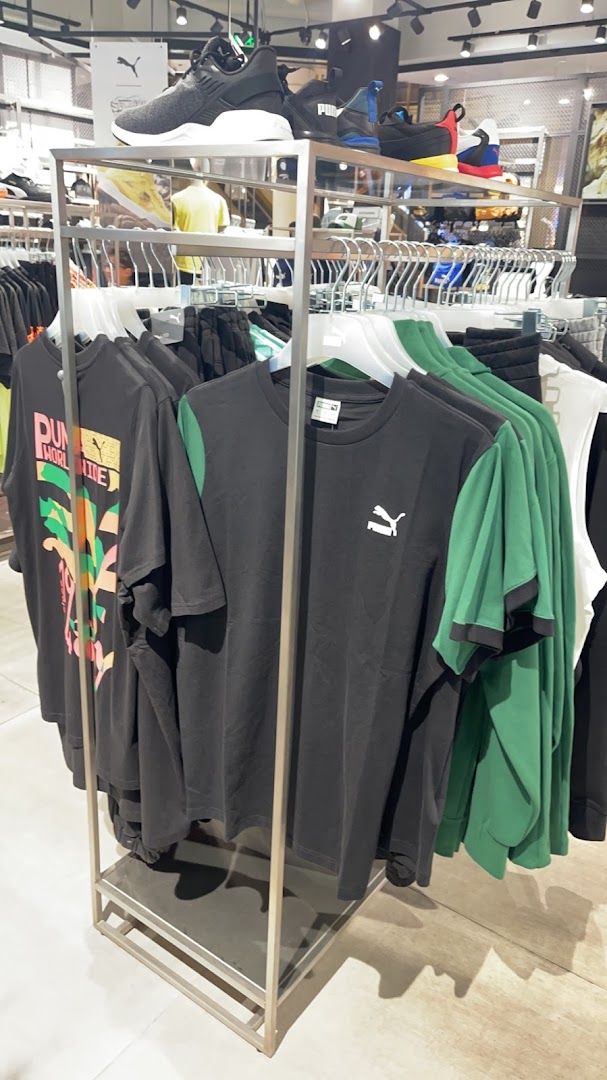 A display of Puma t-shirts and sneakers in a retail store.